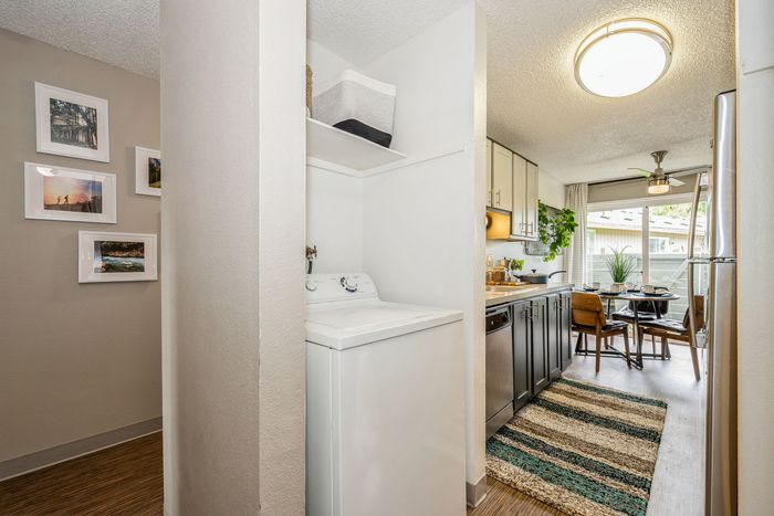 Charming apartment interior featuring a bright, modern kitchen with stainless steel appliances and cozy dining area, complemented by a convenient in-unit washer and stylish decor.