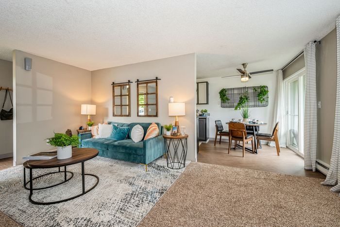 Inviting living space with plush teal sofa, stylish dining area, and lush greenery for a cozy home atmosphere.