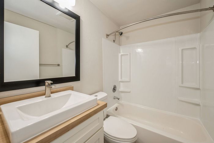 Modern bathroom with a sleek vanity, stylish mirror, and pristine bathtub.