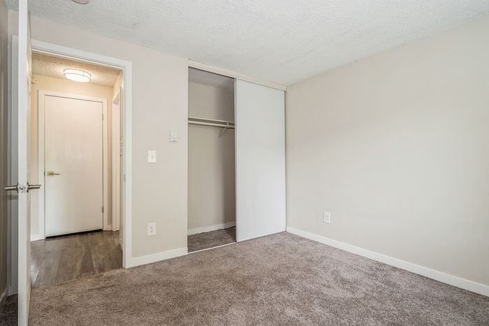Inviting bedroom with plush carpeting, spacious closet, and elegant neutral tones creating a cozy atmosphere.