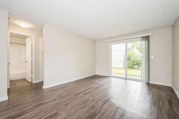 Bright and airy apartment with sleek hardwood floors, offering a serene view through large sliding glass doors.