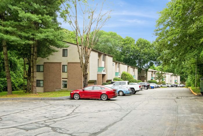 Charming multi-story apartment complex nestled in lush greenery, offering a serene and inviting living environment with ample parking.