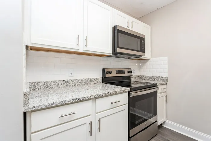 Modern kitchen with sleek granite countertops, stainless steel appliances, and white cabinetry for a stylish touch.