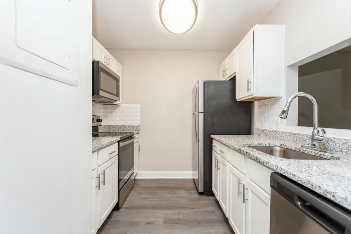 Modern kitchen with sleek granite countertops, stainless steel appliances, and elegant white cabinetry.