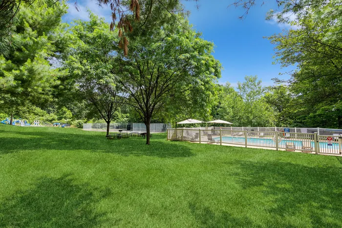 Lush green landscape with a serene swimming pool, shaded picnic tables, and recreational playground. Ideal for relaxation and outdoor activities.