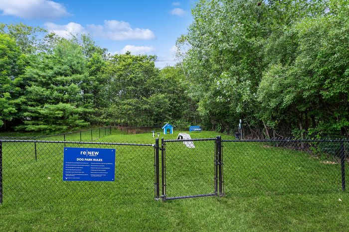 Charming dog park with lush greenery, a playful doghouse, and inviting seating, perfect for pet-friendly living.