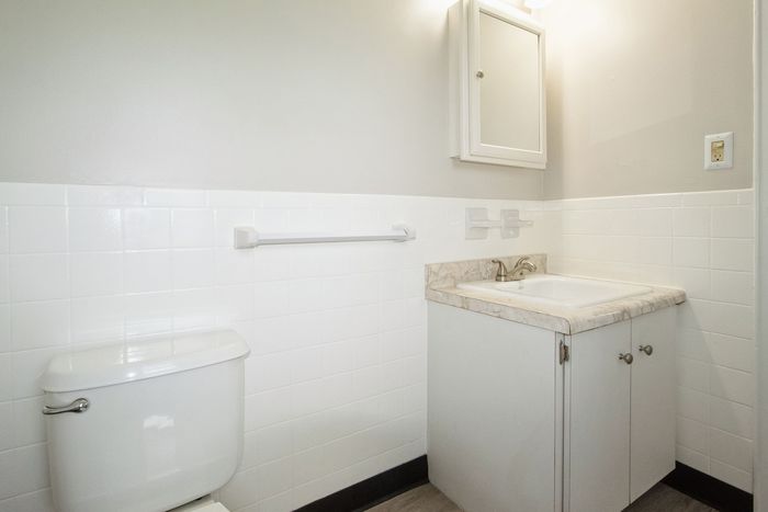 Bright and modern bathroom with sleek white tiles, elegant vanity with marble countertop, and contemporary fixtures.