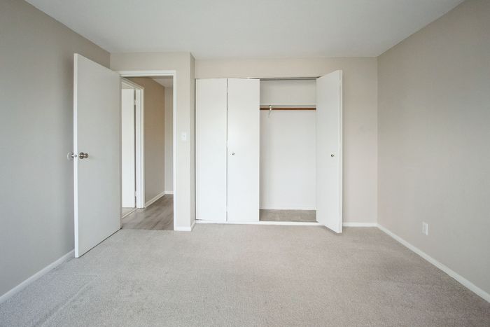 Bright, spacious bedroom featuring plush carpet, neutral walls, and a large closet for ample storage.