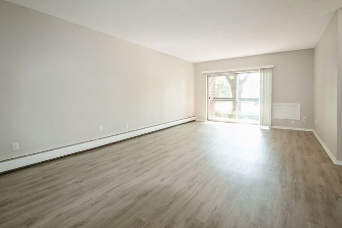 Bright and spacious living area with sleek wood flooring, large window, and abundant natural light.