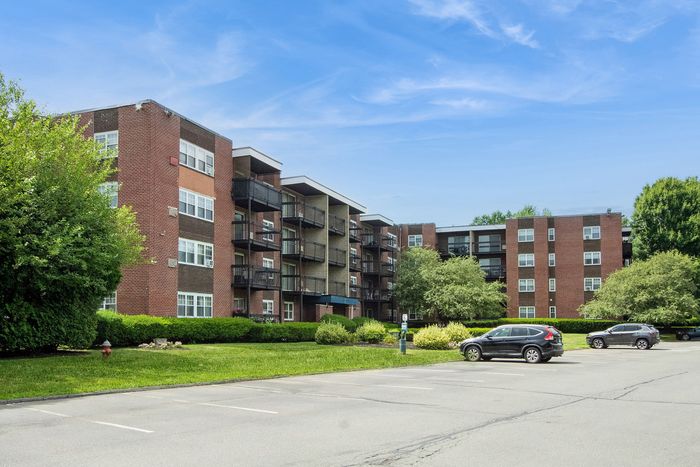 Modern brick apartment complex with spacious balconies and lush green surroundings, perfect for comfortable living.