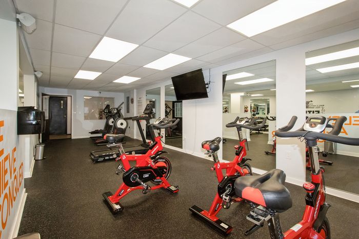 Modern fitness center featuring bright lighting, stationary bikes, treadmills, and wall mirrors for an energizing workout experience.