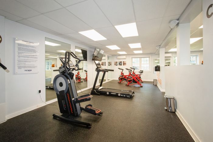 Modern fitness center with high-end exercise equipment, including stationary bikes and a treadmill, set in a bright, welcoming space with ample lighting.