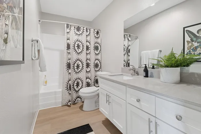Modern bathroom with chic patterned shower curtain, sleek white vanity, and elegant decor.