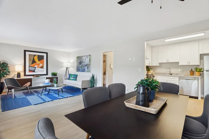 Inviting open-concept living area with elegant dining space and light-filled kitchen, featuring modern decor and vibrant artwork.