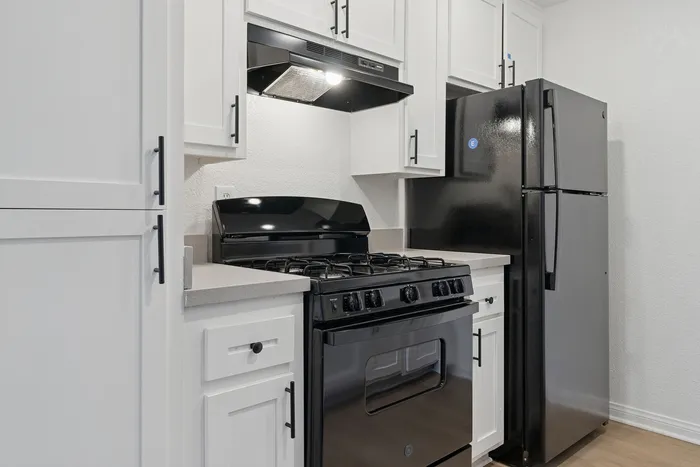 Modern kitchen with sleek black appliances, stylish white cabinetry, and polished countertops, offering a blend of sophistication and functionality.