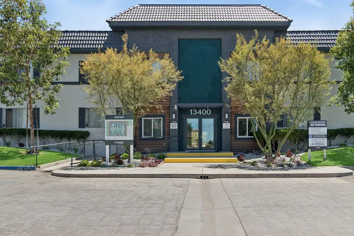Welcoming apartment complex entrance with a modern design, lush landscaping, and vibrant curb appeal.
