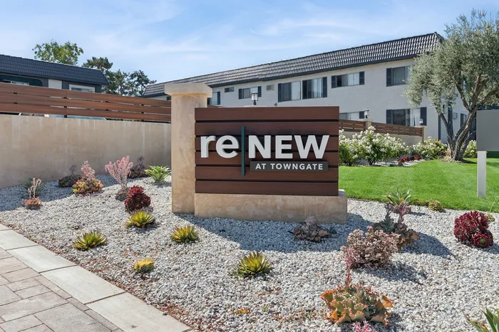 Charming exterior of 'ReNew at Towngate,' featuring modern landscaping with succulents and lush greenery, set against a backdrop of stylish apartment buildings.