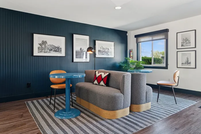 Chic and cozy apartment nook with stylish gray sofa, vibrant blue table, and elegant wall art, perfect for relaxation and conversation.