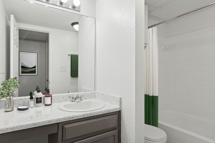 Sleek and modern bathroom with elegant white finishes, stylish granite countertop, and a cozy tub for relaxation.