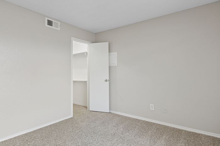 Bright and inviting bedroom with plush carpet flooring, freshly painted walls, and a spacious walk-in closet.
