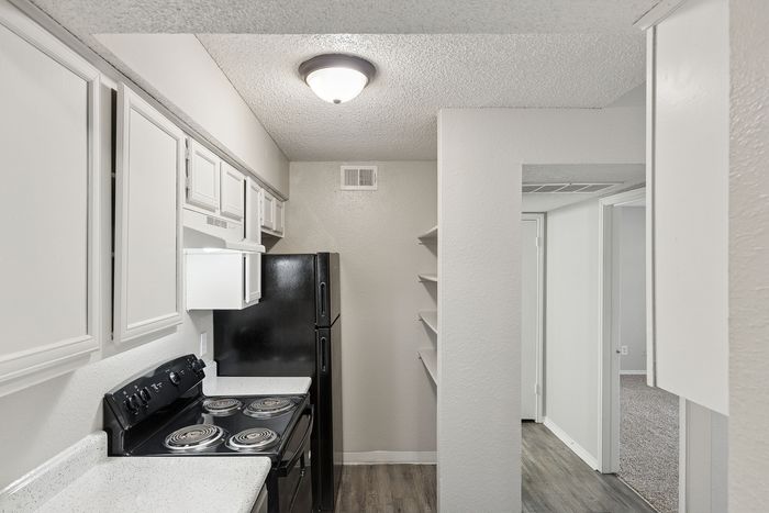 Modern kitchen with sleek black appliances, ample cabinetry, and elegant shelving, perfect for urban living.