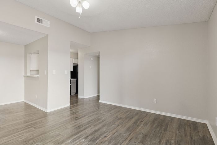 Modern apartment interior with elegant wood flooring, bright open space, and kitchen entry, perfect for a stylish lifestyle.