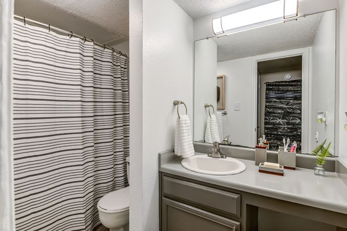Modern bathroom with elegant fixtures, sleek vanity, and stylish striped shower curtain, offering a tranquil and sophisticated ambiance.