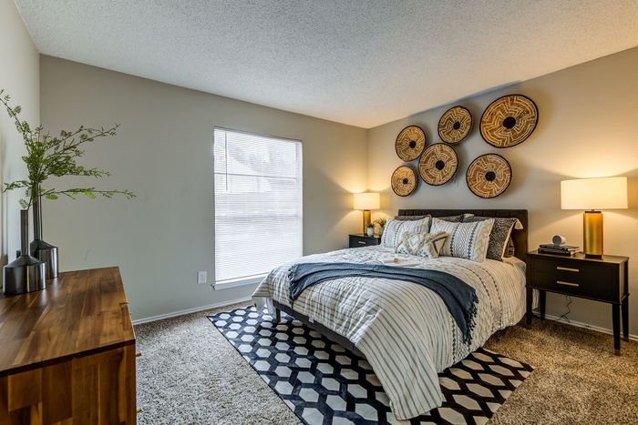 Cozy bedroom with modern decor, featuring elegant wicker wall art, plush carpeting, and ambient lighting for a warm atmosphere.