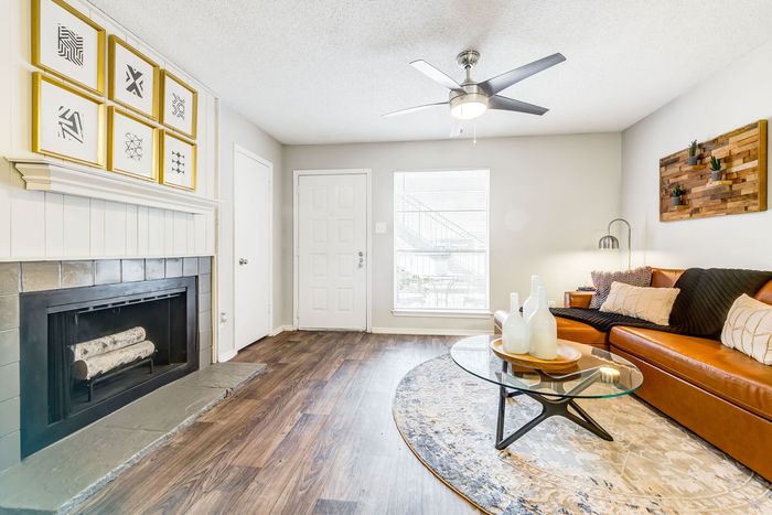 Modern living room with cozy fireplace, stylish artwork, and elegant brown sofa, perfect for relaxation.