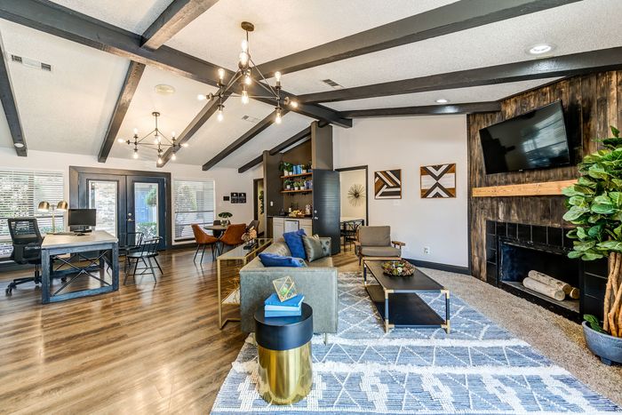 Chic open-concept living space with vaulted ceilings and modern lighting, featuring a cozy seating area, stylish office nook, and a sleek fireplace.