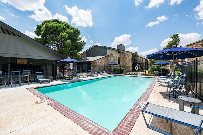Inviting swimming pool area surrounded by comfortable lounge chairs and umbrellas, perfect for relaxation on a sunny day.