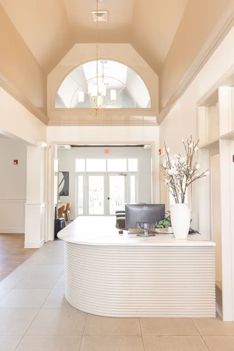 Elegant apartment lobby at ReNew Howard Crossing with high vaulted ceilings, sophisticated lighting, and a modern reception desk adorned with a stylish floral arrangement.