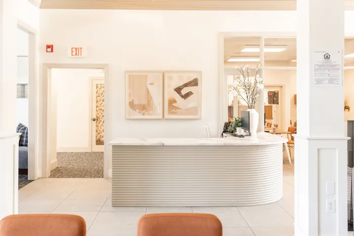 Bright and welcoming apartment reception area at ReNew Howard Crossing  with modern design, featuring artistic wall decor and a chic curved desk.