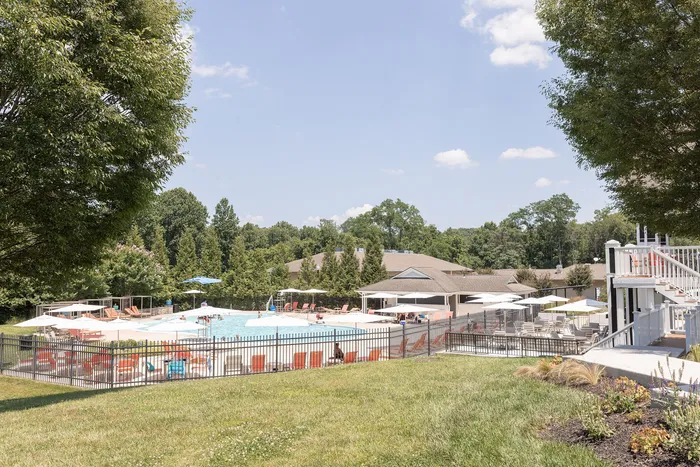 Inviting apartment complex at ReNew Howard Crossing with a sparkling outdoor pool, surrounded by lush greenery and comfortable seating areas.