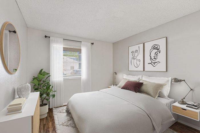 Chic bedroom at ReNew Heights with contemporary art, cozy bedding, and abundant natural light from a large window. A plush plant and minimalist decor complete the stylish ambiance.