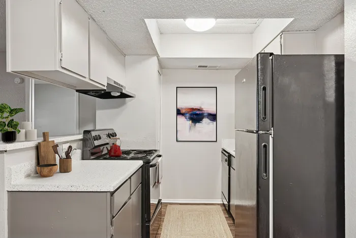 Modern kitchen at ReNew Heights  with sleek black appliances, white countertops, and artistic wall decor, featuring a cozy layout with a touch of elegance.
