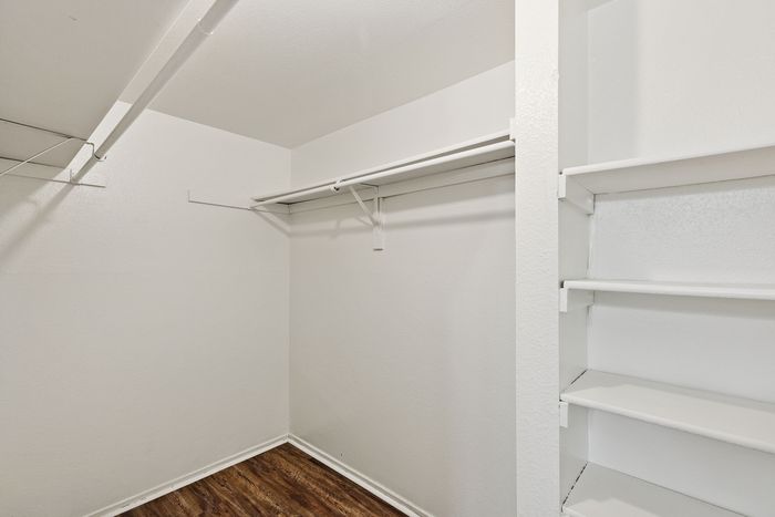 Spacious walk-in closet at ReNew Heights with built-in shelves and clothing rods, perfect for organized storage.