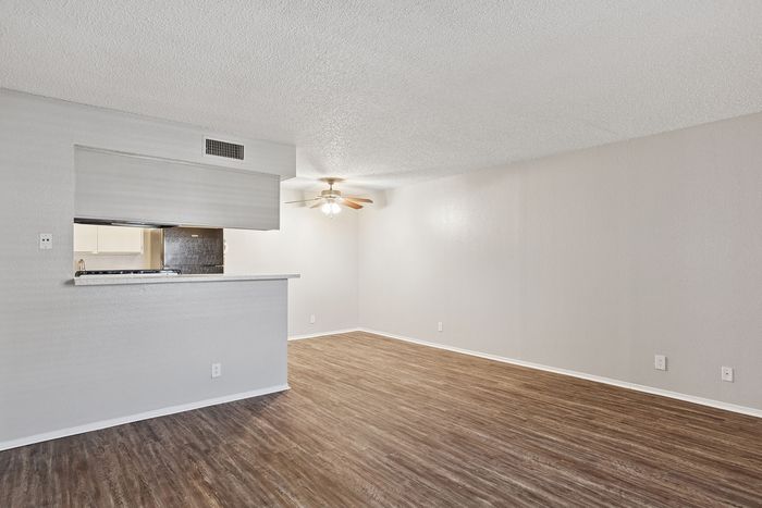 Spacious open-concept living area at ReNew Heights with elegant hardwood floors and modern kitchen pass-through.