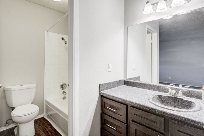 Modern bathroom at ReNew Heights featuring a sleek vanity with granite countertop, stylish fixtures, and a spacious shower-bathtub combo.