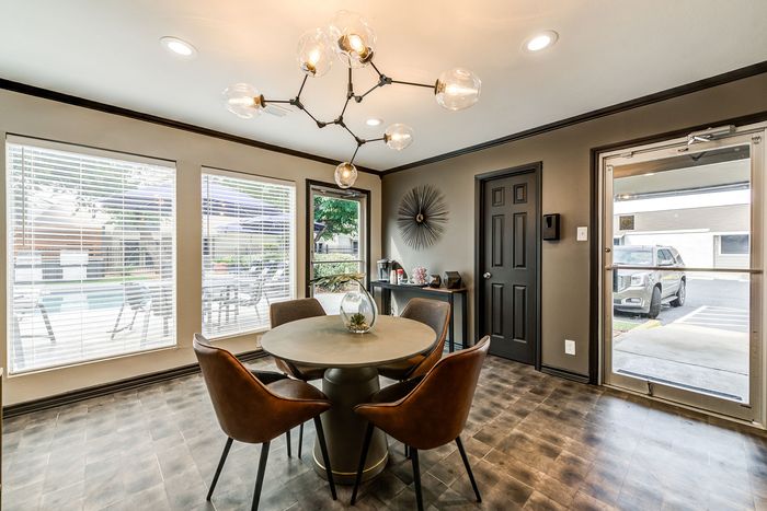 Modern dining space with plush chairs, stylish lighting, and large windows overlooking poolside ambiance.