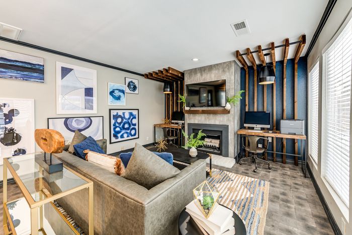 Chic living room with modern art, sleek fireplace, and stylish workspace, offering warmth and elegance.