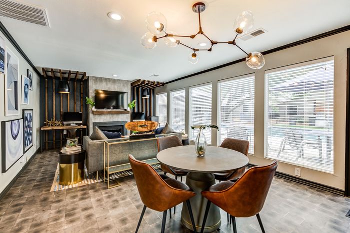 Chic modern living room with stylish decor, large windows overlooking a pool, and a cozy dining area with elegant lighting.