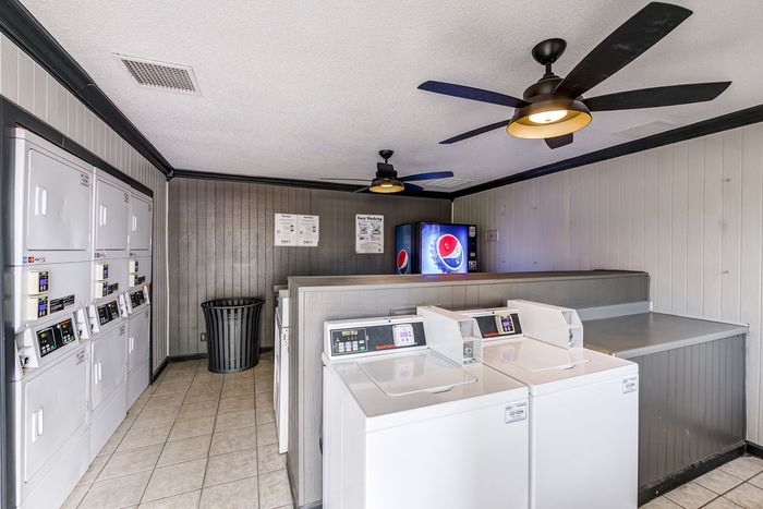 Modern laundry room featuring sleek washing and drying machines with convenient vending machines and ceiling fans for added comfort.