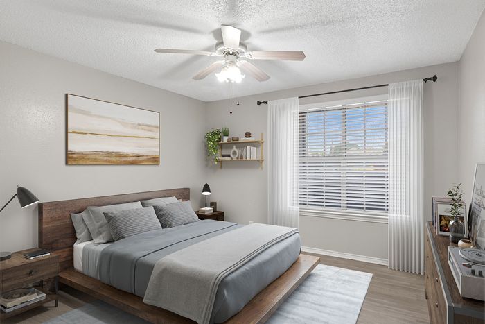 Inviting bedroom with a modern wooden bed, cozy gray bedding, stylish nightstands, and large window letting in natural light.