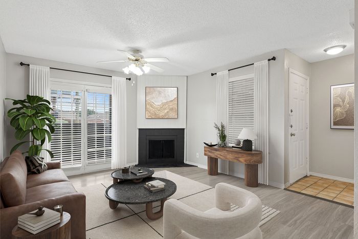 Elegant living room with modern decor, featuring a cozy fireplace, stylish furniture, and abundant natural light through large windows.
