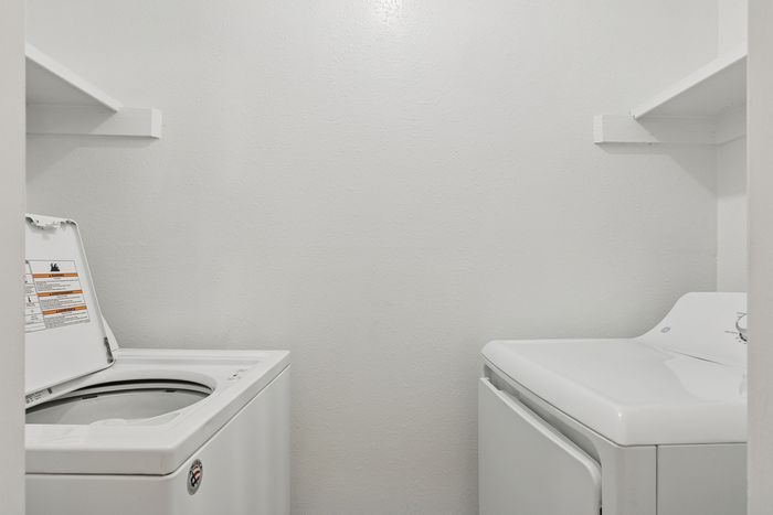 Compact laundry room with modern washer, dryer, and built-in shelves for efficient storage solutions.