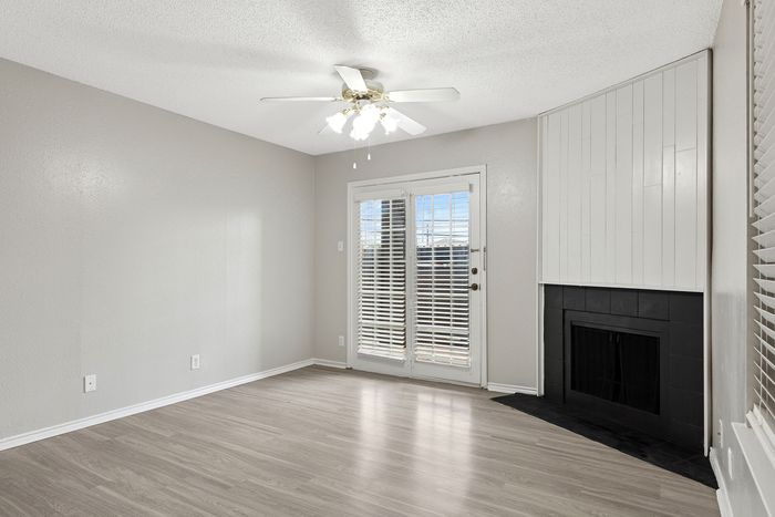 Bright and inviting living room featuring elegant wood flooring, a cozy fireplace, and French doors opening to natural light.