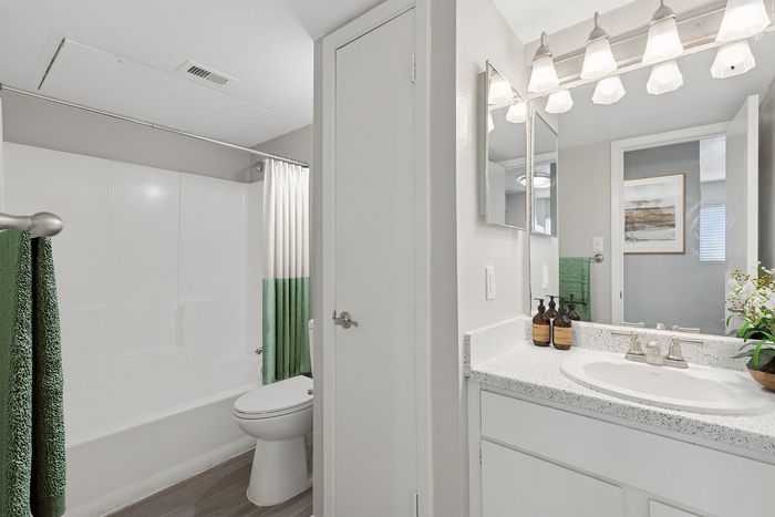 Modern bathroom with elegant lighting, stylish vanity, and cozy bathtub adorned with green accents.