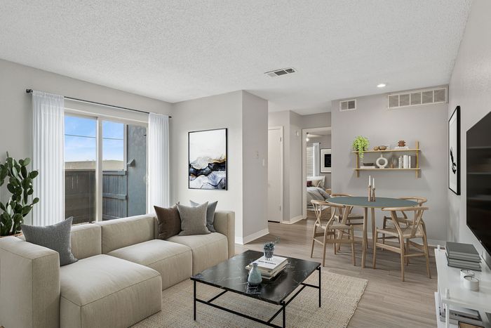 Modern living room with neutral tones, featuring a plush sectional sofa, stylish coffee table, and open dining area with elegant decor.