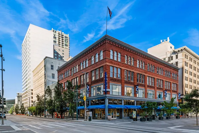 Charming urban building with classic brick architecture, featuring large windows and vibrant street-level shops on a bustling city corner.